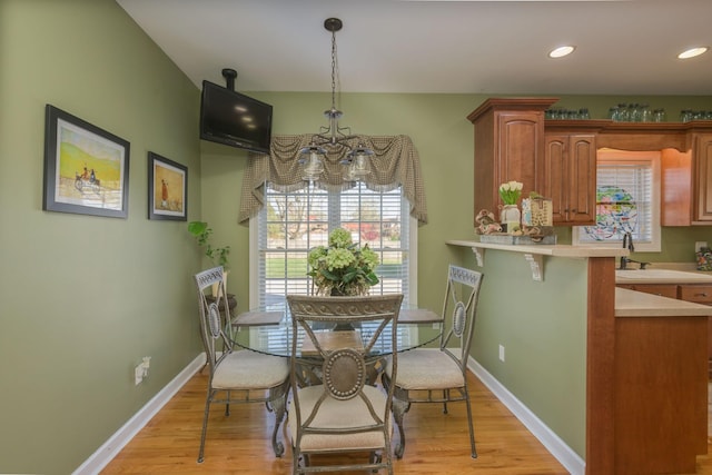 dining area with an inviting chandelier, light wood-style flooring, baseboards, and recessed lighting
