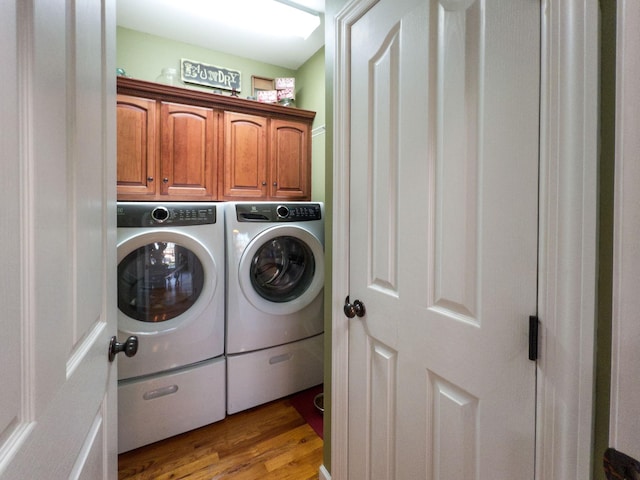 clothes washing area featuring independent washer and dryer, cabinet space, and light wood-type flooring