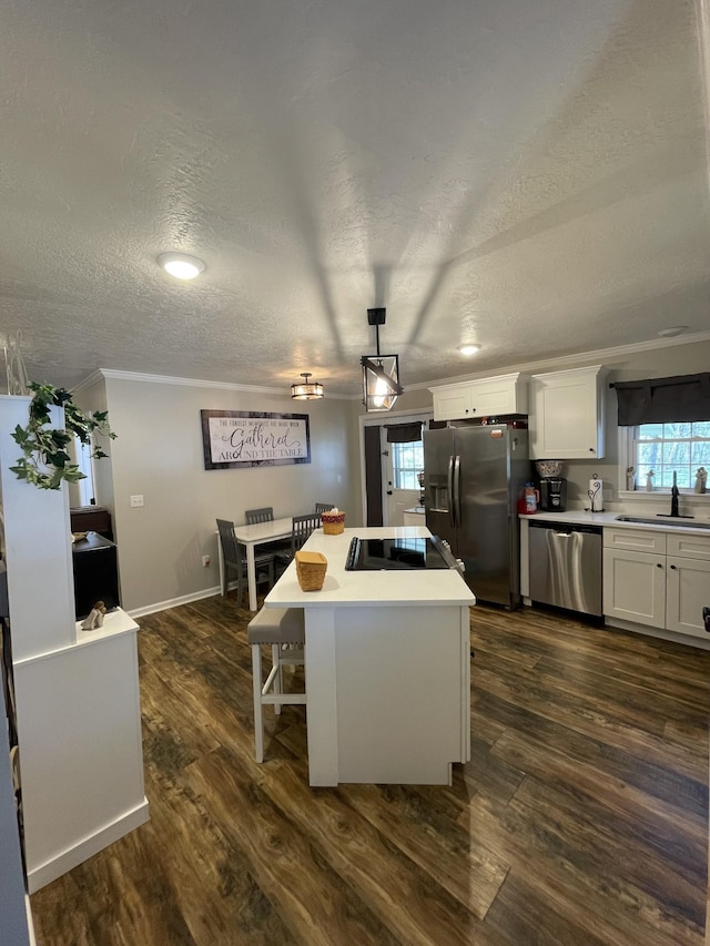 kitchen featuring a sink, appliances with stainless steel finishes, a center island, white cabinets, and dark wood-style flooring