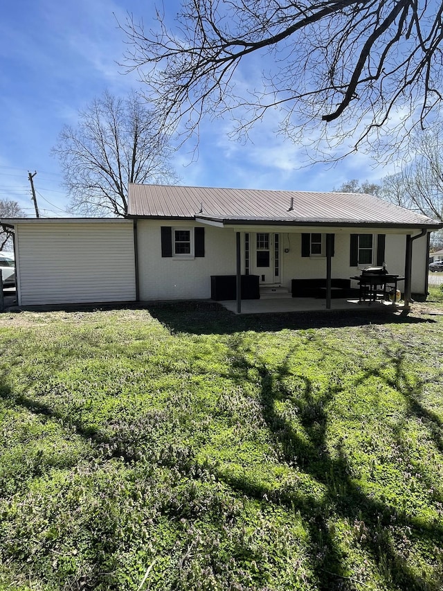 rear view of property with a lawn, metal roof, and a patio area