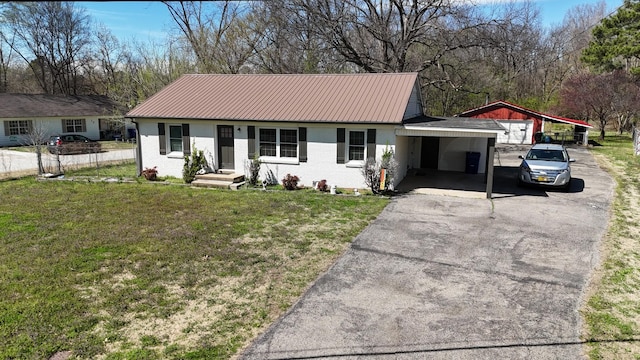 single story home with aphalt driveway, metal roof, a front yard, brick siding, and a carport