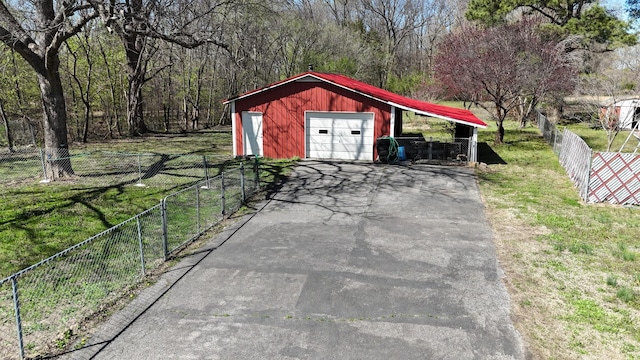 detached garage featuring aphalt driveway and fence
