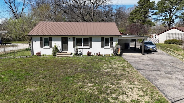 ranch-style house with metal roof, a front yard, an attached carport, brick siding, and driveway