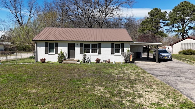 ranch-style home with metal roof, driveway, a front yard, brick siding, and a carport
