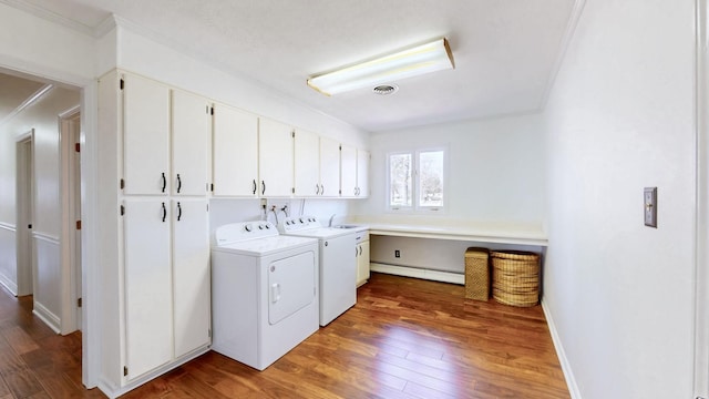 laundry room featuring washer and clothes dryer, a baseboard radiator, cabinet space, and hardwood / wood-style floors