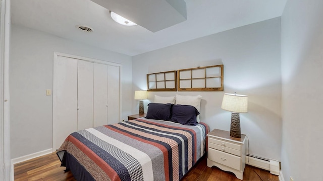 bedroom featuring baseboards, baseboard heating, a closet, and wood finished floors