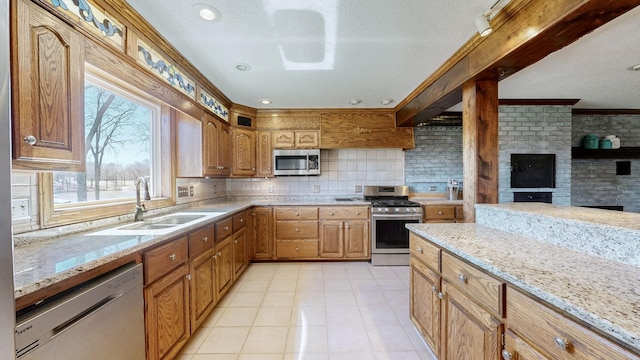 kitchen with a sink, light stone countertops, appliances with stainless steel finishes, and tasteful backsplash