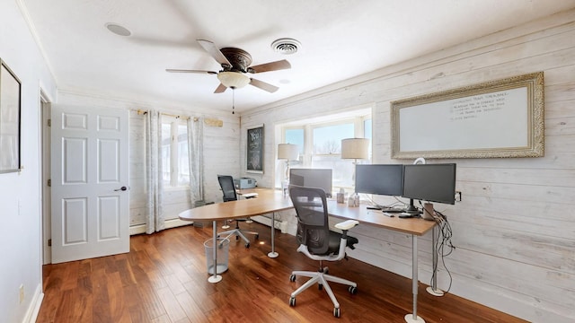 office area with wood walls, baseboard heating, ceiling fan, visible vents, and wood finished floors