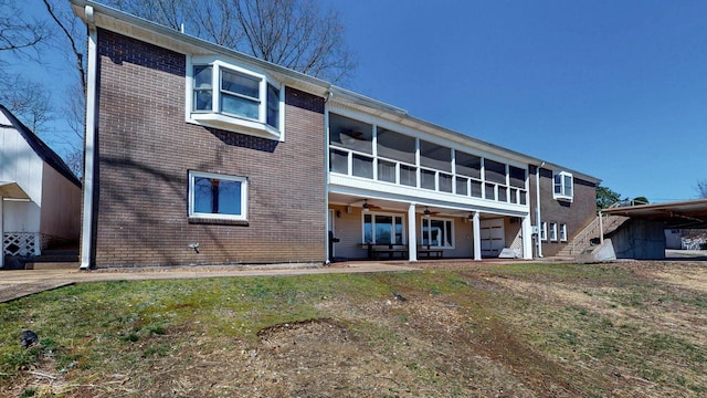 rear view of property featuring brick siding, a sunroom, and a ceiling fan