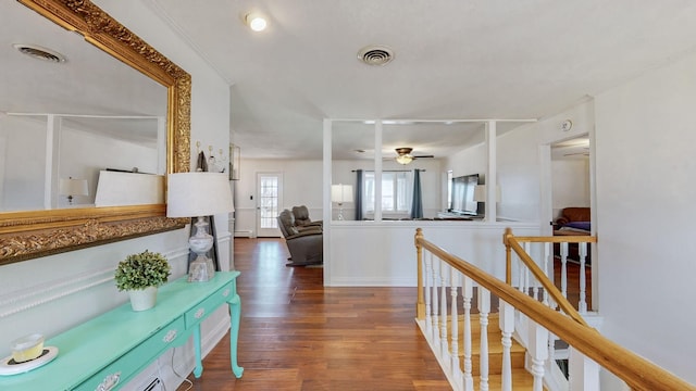 hallway featuring visible vents, an upstairs landing, and wood finished floors