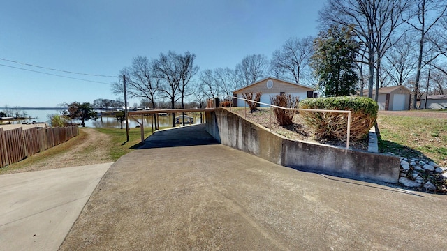 view of front of property featuring a water view, an attached carport, concrete driveway, and fence