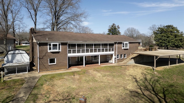 back of property featuring brick siding, stairs, and a patio area