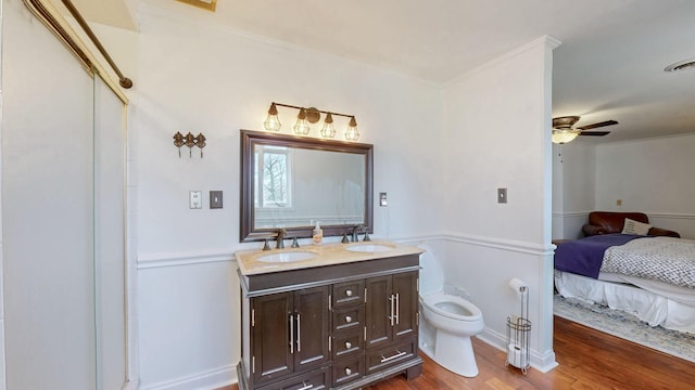 ensuite bathroom with double vanity, wood finished floors, ceiling fan, and a sink