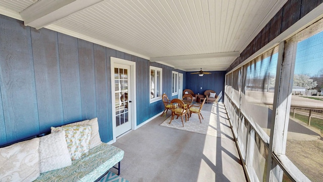 sunroom featuring a wealth of natural light, beam ceiling, carpet, and a ceiling fan