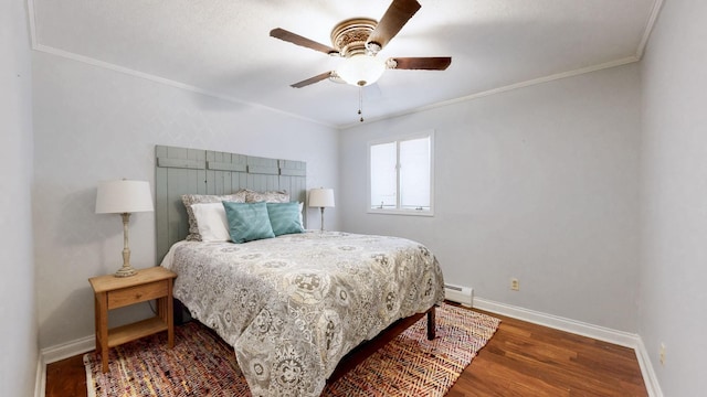 bedroom featuring baseboards, ornamental molding, wood finished floors, ceiling fan, and baseboard heating