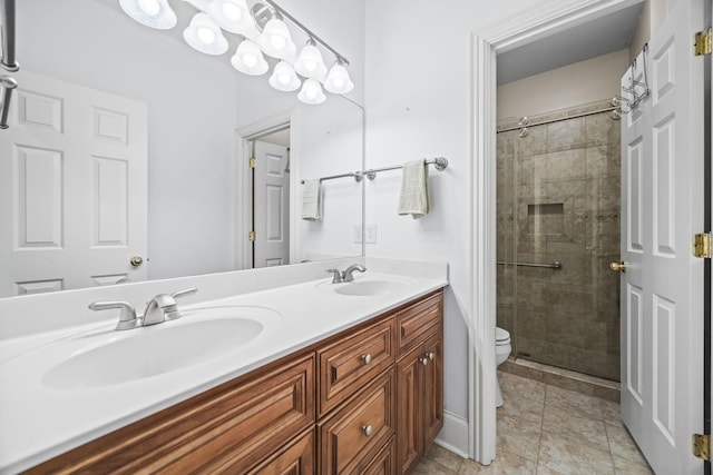 full bath featuring toilet, a stall shower, double vanity, and a sink