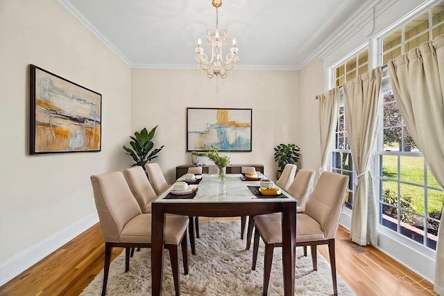 dining room with light wood-style flooring, a notable chandelier, ornamental molding, and baseboards