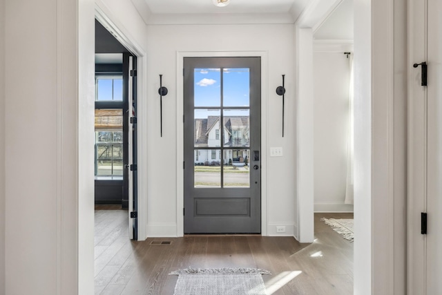 foyer entrance featuring baseboards, visible vents, ornamental molding, and wood finished floors