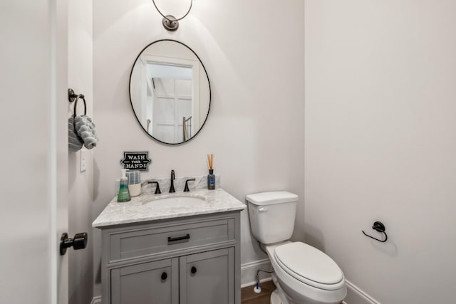 bathroom featuring baseboards, toilet, and vanity