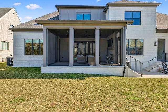 rear view of property with a lawn, a sunroom, and brick siding