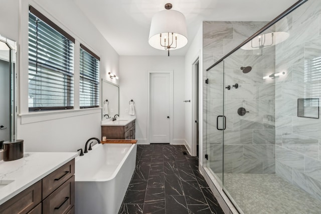full bath with a stall shower, a freestanding tub, two vanities, marble finish floor, and baseboards