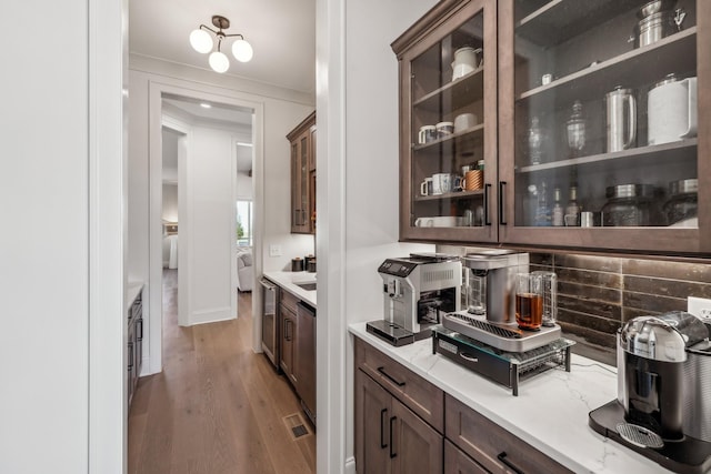 kitchen with decorative backsplash, dishwasher, light wood finished floors, dark brown cabinetry, and glass insert cabinets