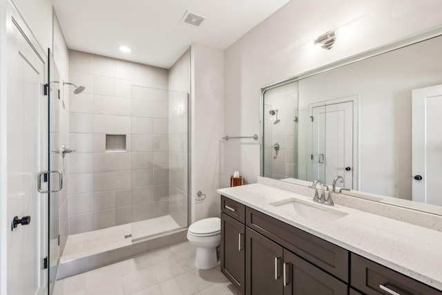 bathroom featuring toilet, vanity, a stall shower, and visible vents