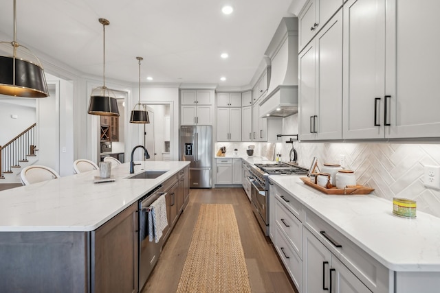 kitchen with a sink, stainless steel appliances, premium range hood, and tasteful backsplash
