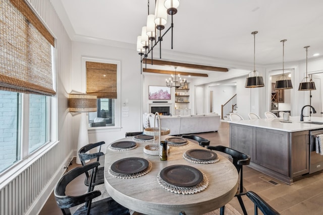 dining room with stairs, a lit fireplace, a chandelier, visible vents, and light wood-style floors