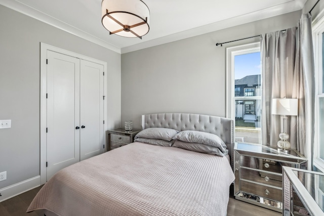 bedroom featuring baseboards, a closet, wood finished floors, and ornamental molding