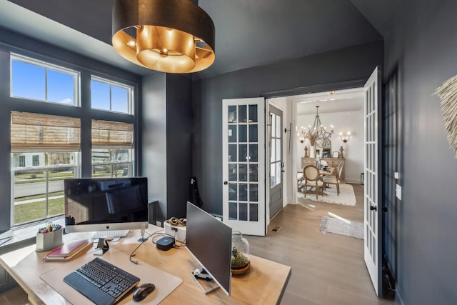 office area with french doors, wood finished floors, and an inviting chandelier