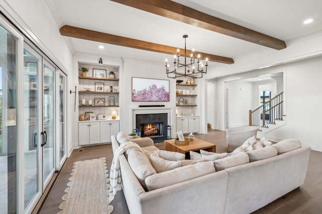 living area featuring dark wood-type flooring, a lit fireplace, a notable chandelier, and beamed ceiling