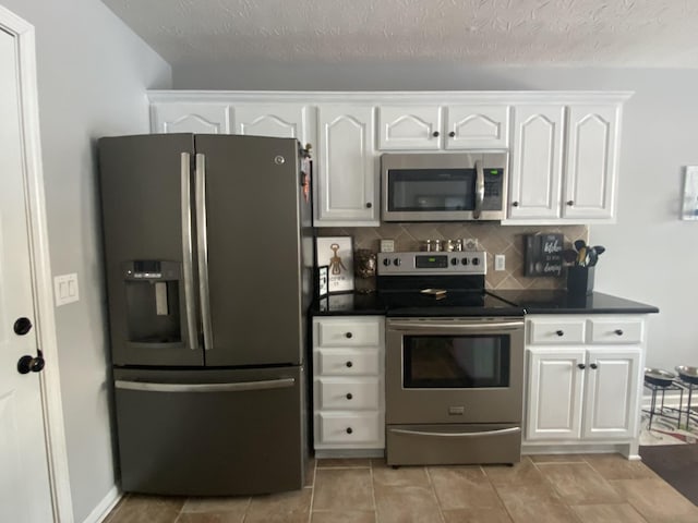 219 Wagoners Way, Westmoreland, TN 37186 - kitchen with a textured ceiling, white cabinets, stainless steel appliances, dark countertops, and backsplash