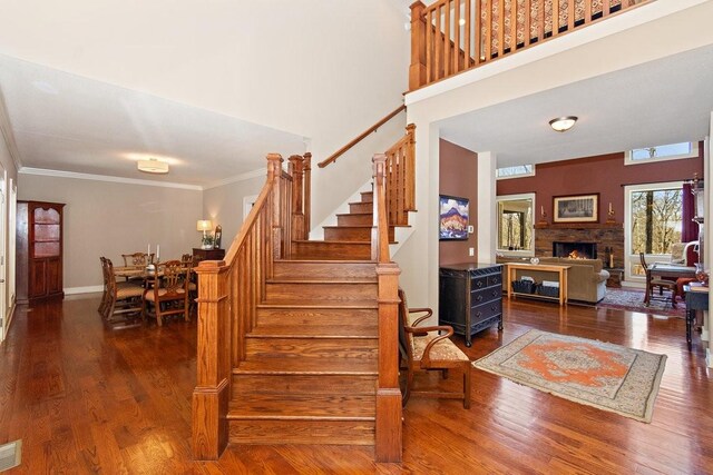 1748 Riverhaven Dr, Adams, TN 37010 - staircase with a warm lit fireplace, wood finished floors, baseboards, visible vents, and ornamental molding