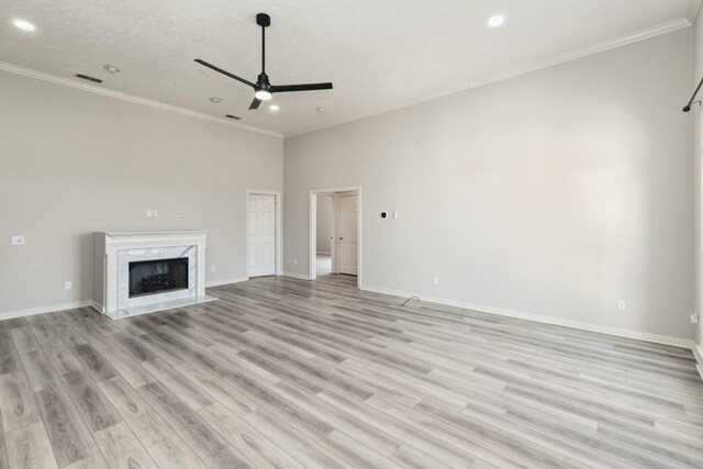 unfurnished living room with crown molding, light wood-type flooring, baseboards, visible vents, and ceiling fan