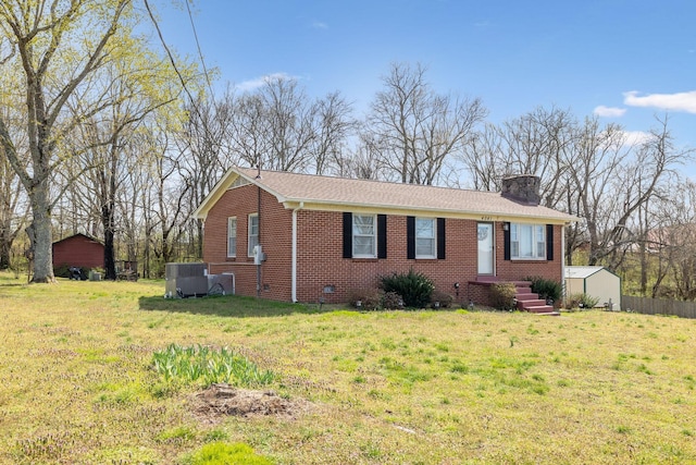 view of front of house featuring brick siding, a front lawn, and a chimney