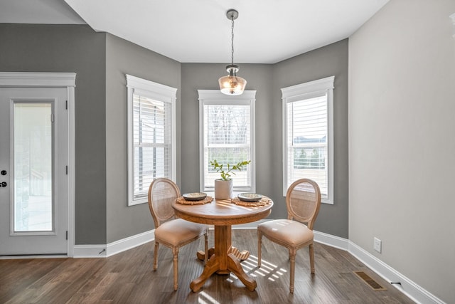 dining space with baseboards, visible vents, and wood finished floors