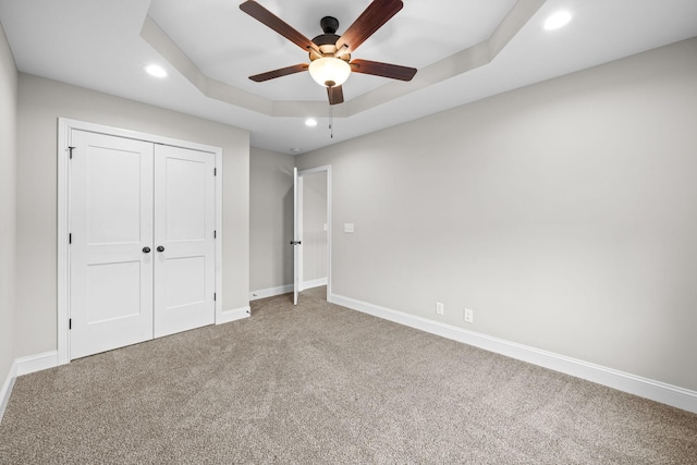 unfurnished bedroom featuring baseboards, recessed lighting, carpet flooring, and a raised ceiling