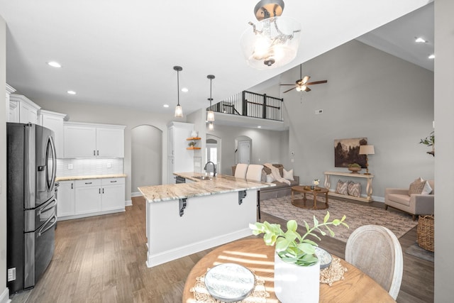 kitchen featuring ceiling fan, arched walkways, a sink, stainless steel refrigerator with ice dispenser, and open floor plan