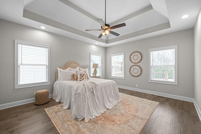 bedroom with baseboards, dark wood-style floors, a tray ceiling, and recessed lighting