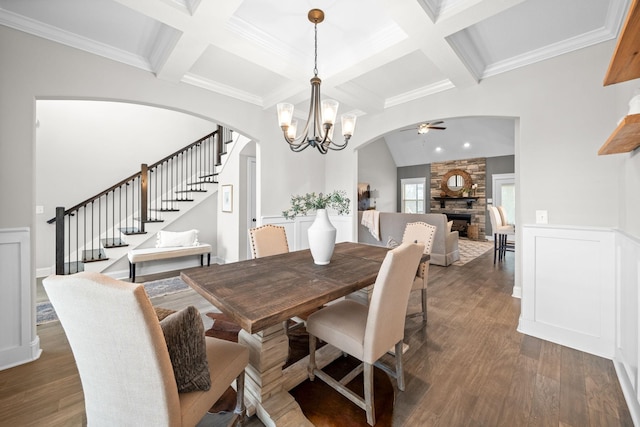dining area with stairs, beam ceiling, arched walkways, dark wood finished floors, and ceiling fan with notable chandelier
