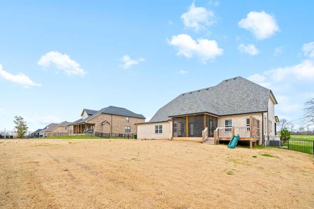 rear view of house with a fenced backyard and a sunroom