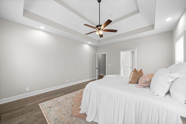 bedroom featuring a raised ceiling, baseboards, and wood finished floors