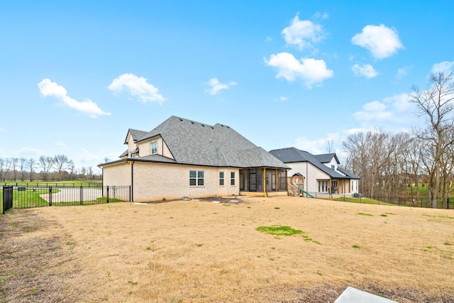 back of property with a sunroom, a shingled roof, fence, and a lawn