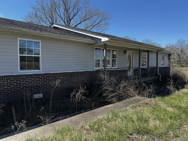 ranch-style home featuring covered porch and brick siding