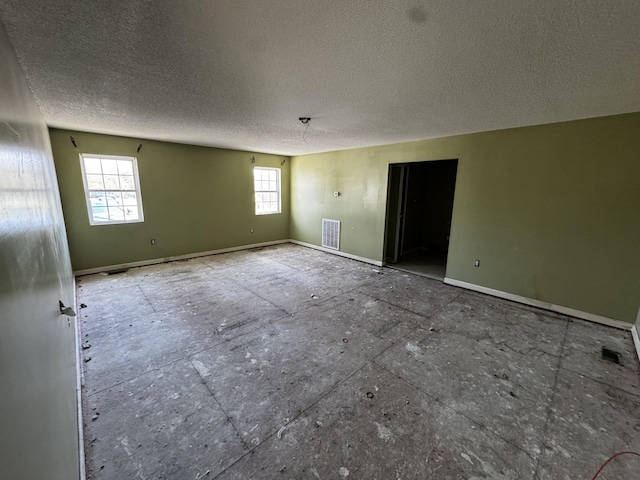 spare room with baseboards, a textured ceiling, and visible vents