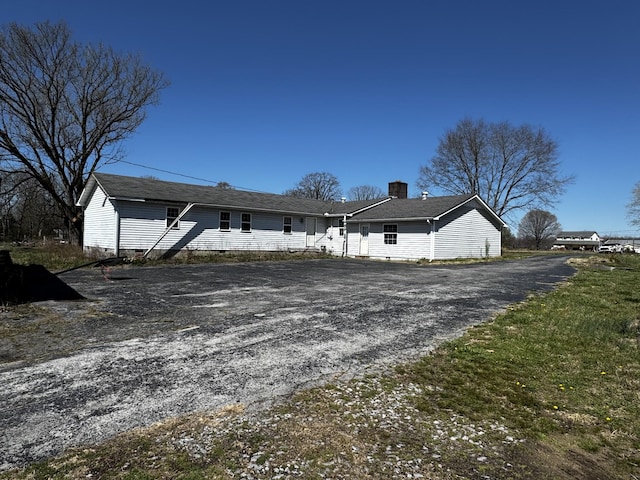 exterior space with a chimney, gravel driveway, and crawl space