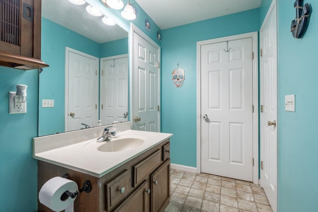 bathroom featuring vanity, stone finish floor, and baseboards