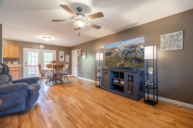 living room featuring baseboards, light wood-style floors, and ceiling fan