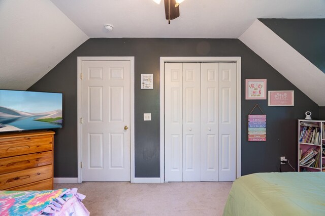 bedroom featuring vaulted ceiling, baseboards, a ceiling fan, light carpet, and a closet